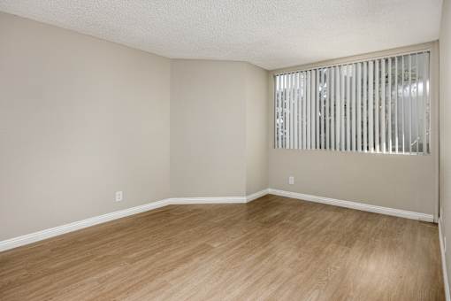 Empty room with wooden floor and a window with blinds.
