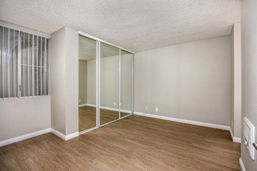 A room with a sliding glass door and wooden flooring.