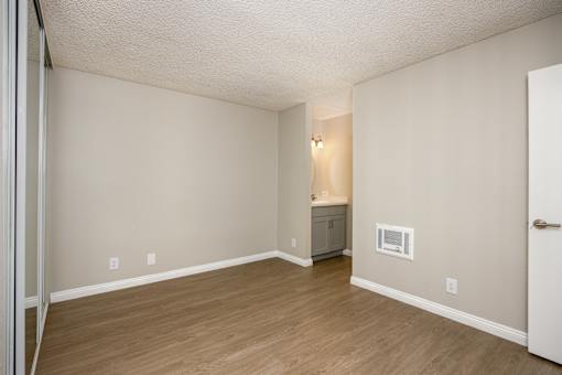 A room with a wooden floor and a small cabinet with a microwave.