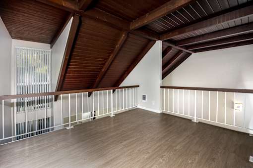 A room with wooden floors and a balcony with white railings.