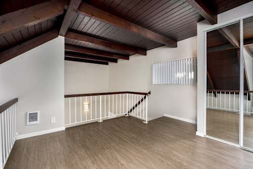 A room with a wooden floor and a staircase with a railing.