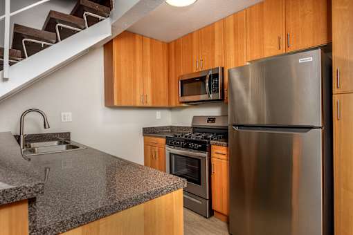 A kitchen with a stainless steel refrigerator and wooden cabinets.