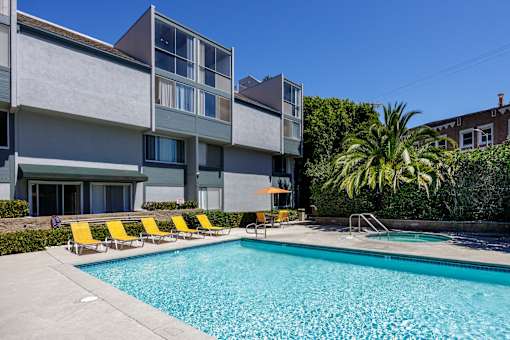 a swimming pool with yellow chairs in front of a building