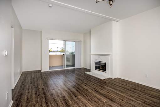 A large, empty room with a fireplace and wooden floors.