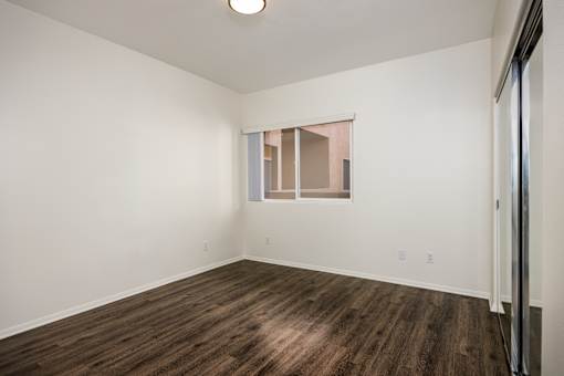 A room with wooden flooring and a window with blinds.
