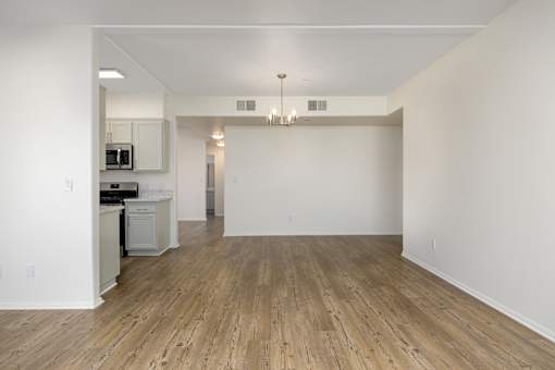 an empty living room and kitchen with white walls and wood flooring