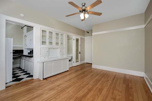 an empty living room and kitchen with wood floors and a ceiling fan