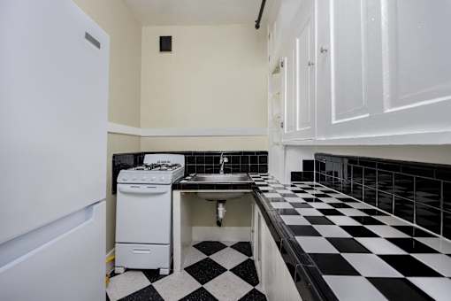 a kitchen with black and white checkered floors and a white stove and sink