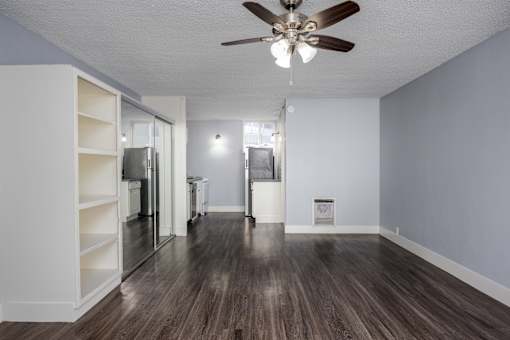 A room with a ceiling fan and wooden flooring.