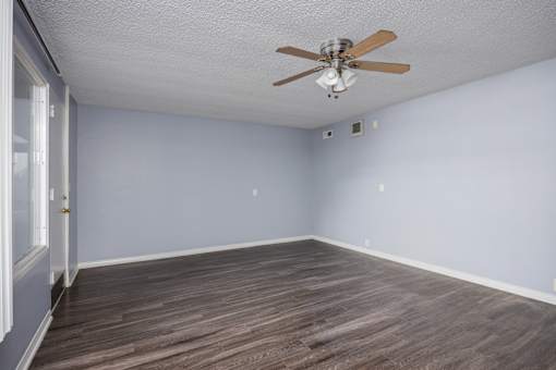 A room with a ceiling fan and wooden flooring.