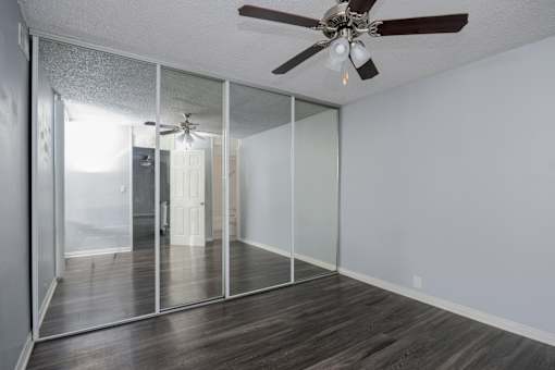 A room with a ceiling fan and sliding glass doors.