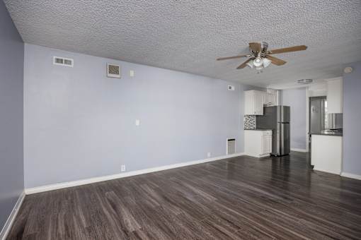 A room with a ceiling fan and a refrigerator.