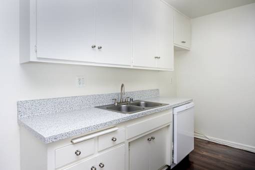 an empty kitchen with white cabinets and a sink