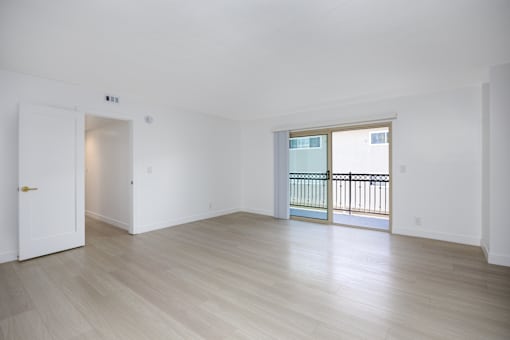 an empty living room with wood floors and a balcony