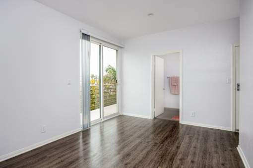a living room with white walls and wooden floors and sliding glass doors
