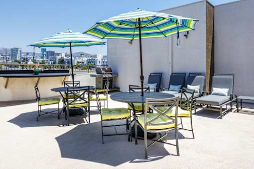 a patio with tables and chairs and umbrellas on the roof of a building