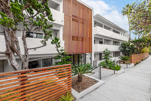 A modern building with a wooden fence and plants in front.