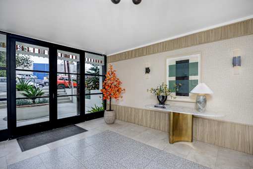 A hallway with a gold console table and a vase of orange flowers.