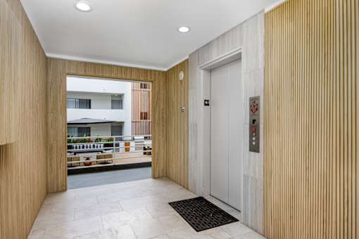 A hallway with a white door and a black mat on the floor.