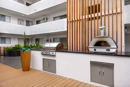A modern outdoor kitchen with a grill and a potted plant.