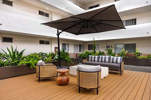 A patio with a wicker chair and a large umbrella.