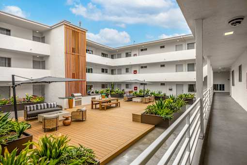 A modern building with a wooden deck and plants.