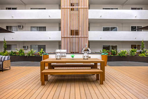 A wooden bench with two vases on it in front of a building.