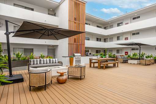 A patio with a black umbrella and wooden furniture.