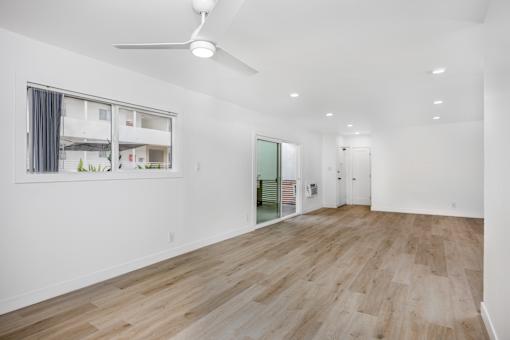 A room with a ceiling fan and wooden flooring.