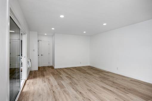A room with wooden flooring and white walls.
