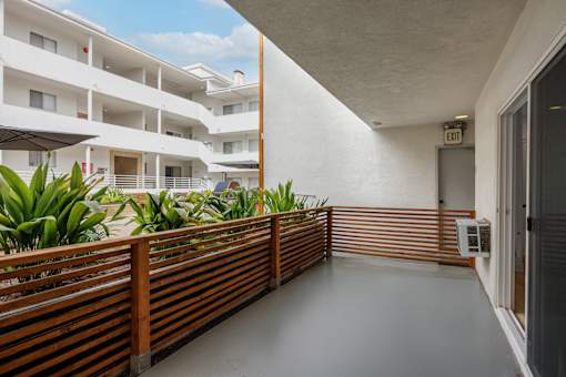 A long hallway with a railing and plants on the side.