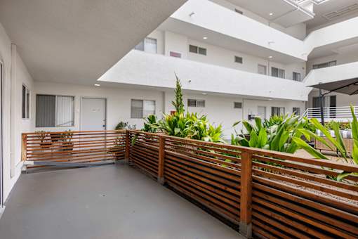 A white building with a balcony and plants.