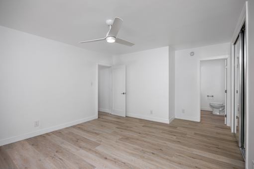 A room with a ceiling fan and wooden flooring.