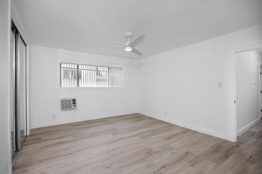 A room with a ceiling fan and a window with blinds.