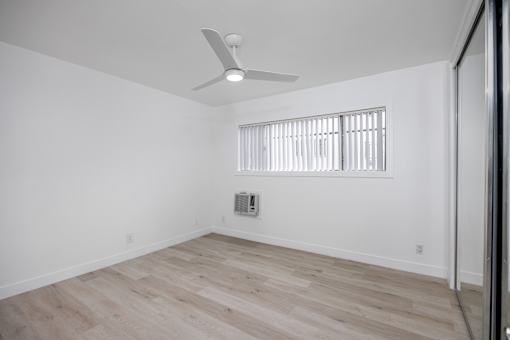 A room with a ceiling fan and a window with blinds.