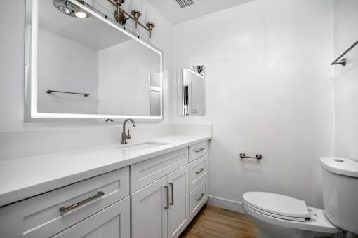 A white bathroom with a toilet, sink, and mirror.