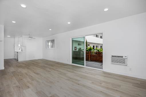 A room with a wooden floor and a glass door leading to a balcony.