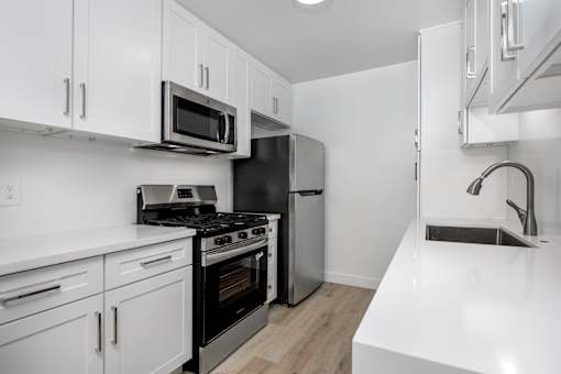 A kitchen with white cabinets and black appliances.