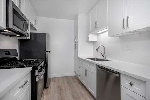 A modern kitchen with white cabinets and stainless steel appliances.
