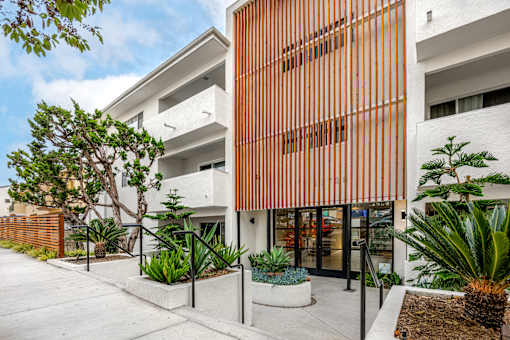 A modern building with a white and orange facade and a landscaped courtyard.