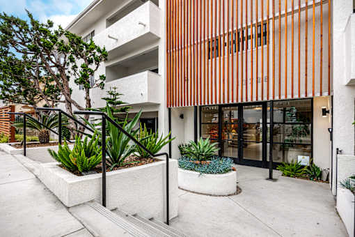 A modern building with a white and orange facade and a small garden in front.