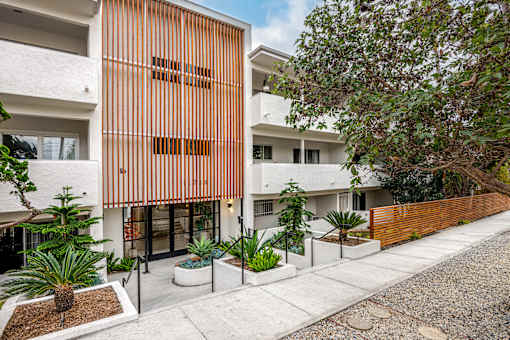 A modern building with a white and orange facade and a gravel driveway in front.