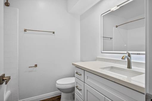 A white bathroom with a toilet, sink, and mirror.