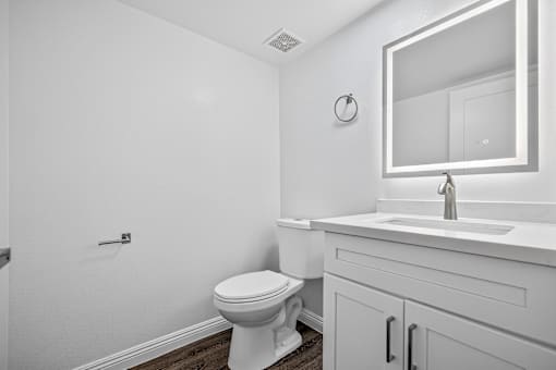 A white bathroom with a toilet, sink, and mirror.
