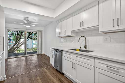 A modern kitchen with white cabinets and a wooden floor.