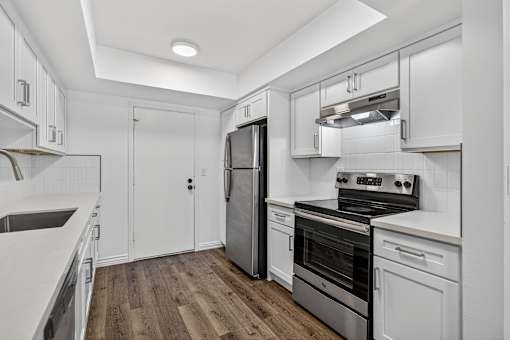 A modern kitchen with white cabinets and stainless steel appliances.