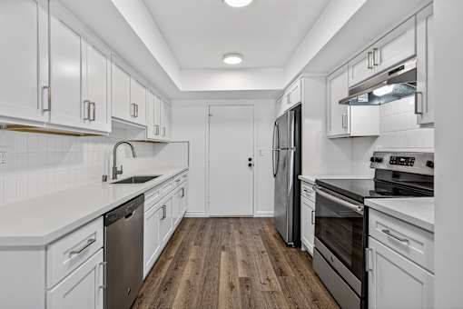 A kitchen with white cabinets and black appliances.