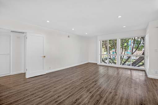A room with wooden flooring and a view of trees through the window.