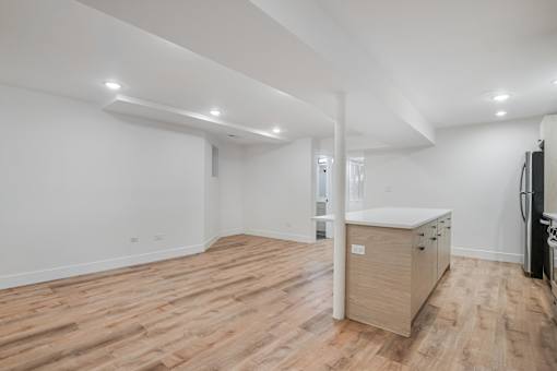A spacious room with wooden flooring and white walls.