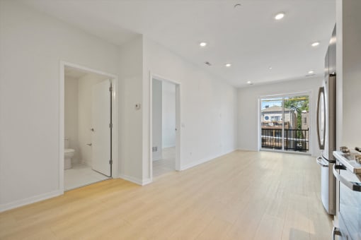 a living room with white walls and a door leading to a bathroom